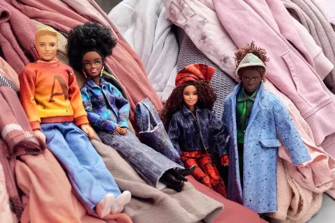 La colección de moda en tamaño muñeca, realizada con residuos textiles, sobre un fondo del basurero de ropa, ropa infantil y textiles.